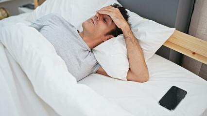 Obraz na płótnie Canvas Young hispanic man stressed lying on bed at bedroom
