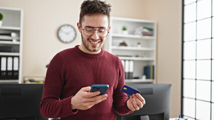 Young hispanic man business worker shopping with smartphone and credit card at office