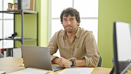 Fototapeta premium Young hispanic man business worker using laptop with serious face at office