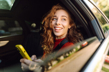 Smiling woman in a taxi car with a mobile phone in her hands. Concept of transport, technology, transportation.