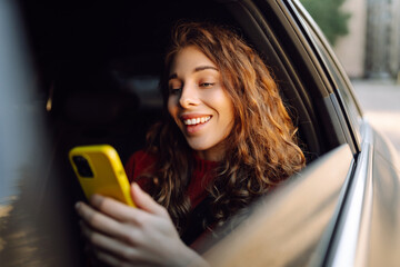 Smiling woman in a taxi car with a mobile phone in her hands. Concept of transport, technology, transportation.
