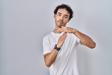 Hispanic man standing over isolated background doing time out gesture with hands, frustrated and serious face