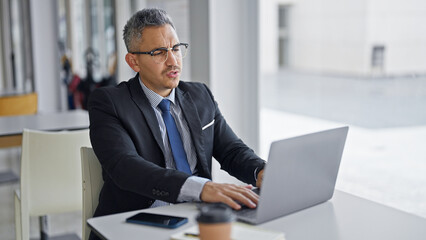 Fototapeta na wymiar Young hispanic man business worker wearing glasses using laptop at office