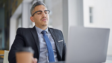 Young hispanic man business worker wearing glasses using laptop at office