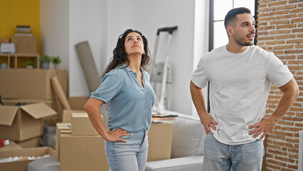 Man and woman couple standing together looking around at new home