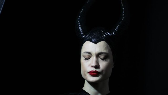  beautiful woman with devil witch horns in sorceress costume. Woman in Halloween costume posing against black background.