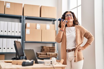 Middle age hispanic woman working sending voice message at ecommerce