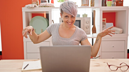 Fototapeta na wymiar Young woman using laptop dancing at dinning room