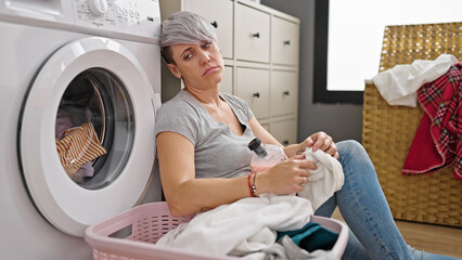 Young woman leaning on washing machine tired at laundry room