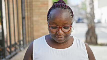 Relaxed, overweight african american woman with braids, sporting cool glasses, seriously looking...