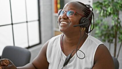 Confident african american woman happily working as a business executive, wearing a headset, and...