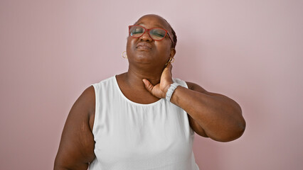 Worried african american woman, overweight and with braids, suffering serious cervical pain, unhappily standing over an isolated pink background wall