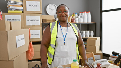 Confident african american woman volunteer, smiling and standing proud at charity center. working...