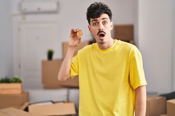 Hispanic man holding bitcoin at new home smiling with a happy and cool smile on face. showing teeth.