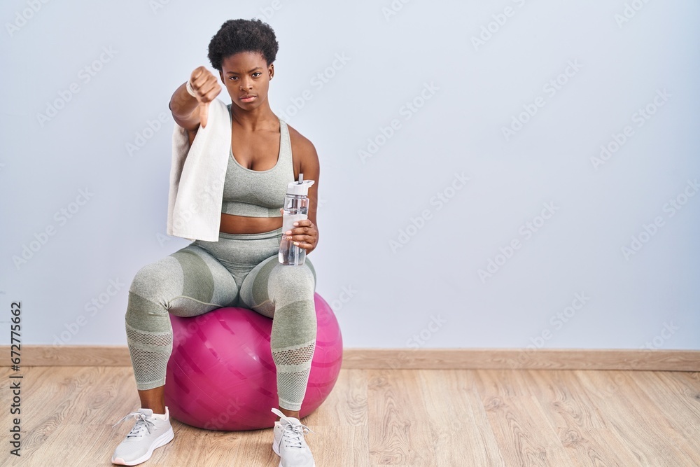 Canvas Prints African american woman wearing sportswear sitting on pilates ball looking unhappy and angry showing rejection and negative with thumbs down gesture. bad expression.