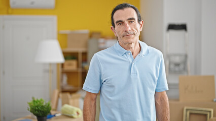 Middle age man standing with serious face at new home