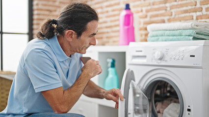 Middle age man washing clothes at laundry room
