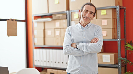 Middle age man ecommerce business worker standing with arms crossed gesture smiling at office