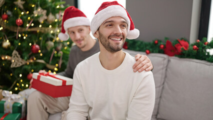 Two men couple celebrating christmas holding gift at home