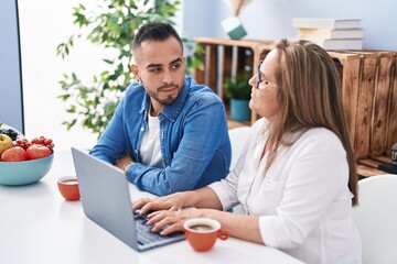 Man and woman mother and son drinking coffee using laptop at home