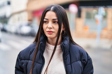 Young beautiful hispanic woman looking to the side with relaxed expression at street