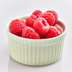  Delicious group of raspberries on ceramic bowl over isolated white background