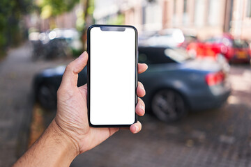 Man holding smartphone showing white blank screen at car parking