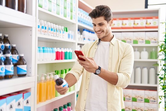Young hispanic man customer make photo by smartphone to medicine bottle at pharmacy