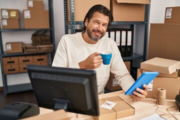 Middle age man ecommerce business worker using touchpad drinking coffee at office