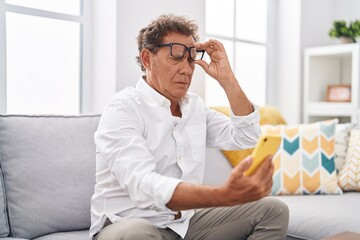 Middle age man having vision problem to see smartphone at home
