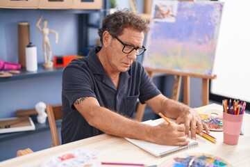 Middle age man artist drawing on notebook at art studio