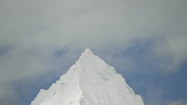 ice covered glacier of a pyramid shaped mountain at laguna paron lagoon in the high andes mountains of the cordillera blanca at huascaran, Peru, with snow covered mountain peaks on a bright sunny day.