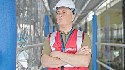 Young caucasian man builder standing with arms crossed gesture and serious face at construction place