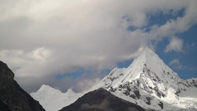 ice covered glacier of a pyramid shaped mountain at laguna paron lagoon in the high andes mountains of the cordillera blanca at huascaran, Peru, with snow covered mountain peaks on a bright sunny day.