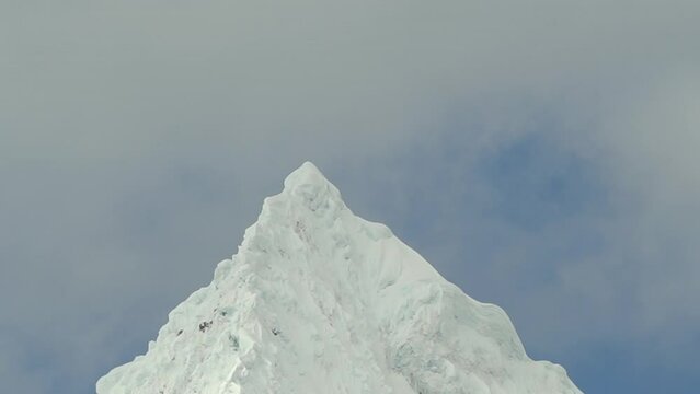 ice covered glacier of a pyramid shaped mountain at laguna paron lagoon in the high andes mountains of the cordillera blanca at huascaran, Peru, with snow covered mountain peaks on a bright sunny day.