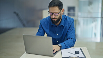 Young hispanic man business worker using laptop working at the office