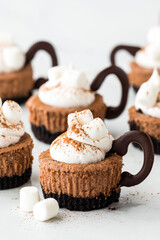 Hot cocoa cheesecake minis topped with whip cream and marshmallows.