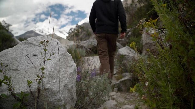 young caucasian man hiking through the mountainous landscape of the cordillera blanca in the Andes mountains of Peru near laguna Paron.
