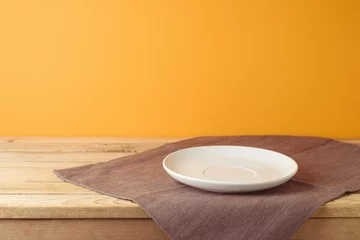 Fotobehang Empty white plate with tablecloth on wooden table over orange wall background. Thanksgiving  mock up for design and product display © maglara