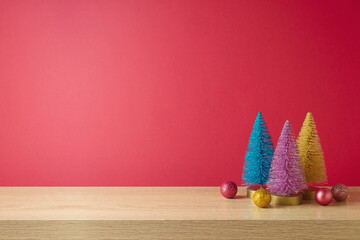 Modern wooden table with colorful pine tree decoration over pink background.  Christmas mock up for...