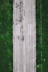 Aerial view of a highway with trees lining either side of the road, surrounded by lush green grass