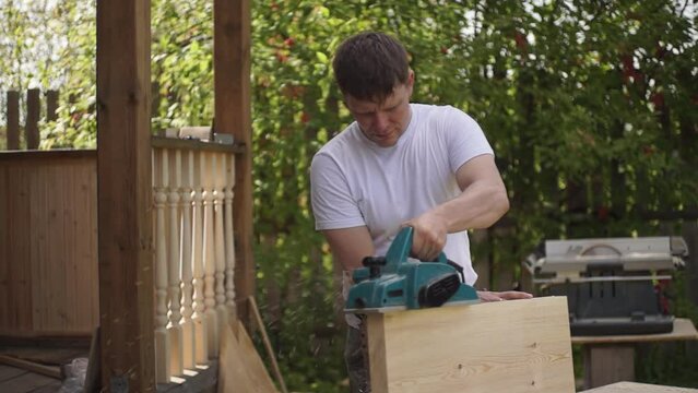 wood processing. a man planes a wooden board using an electric planer. a man works with a power tool. Slow motion video. High quality video in FullHD format.