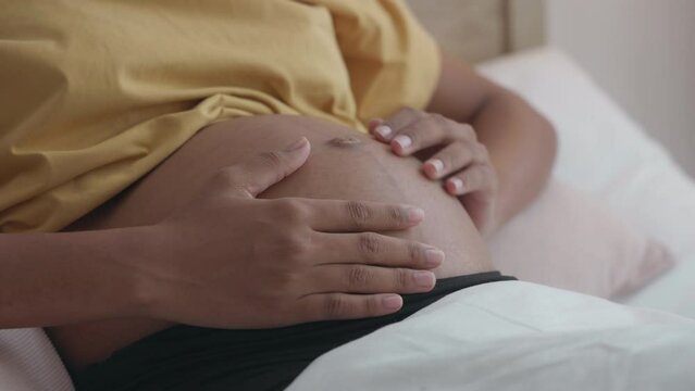 Close-up of African Young Adult Loving Embrace of Pregnancy in Bed