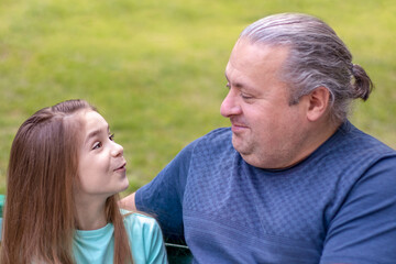 Obraz premium Father and daughter communicate, talk, in the park. Fatherhood, lifestyle, parenting, childhood and family life concept.