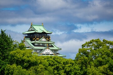 Fototapeta premium Grand wooden Asian-style building standing tall surrounded by lush green foliage