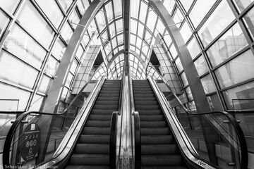 Black and white shot of escalators traveling in a downward direction in a commercial building