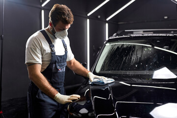 man cleaning car with cloth and detergent liquids, car detailing or valeting concept. In auto...