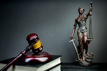 Themis, judge's gavel and books on jurisprudence on a wooden background. Legal and law concept.