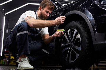 Obraz na płótnie Canvas auto mechanic worker lubricate discs or wheels of automobile, using oil liquid in small bottle, at automobile repair and renew service station shop
