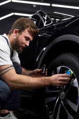 side view on auto mechanic worker lubricate discs or wheels of automobile, using oil liquid in small bottle, at automobile repair and renew service station shop